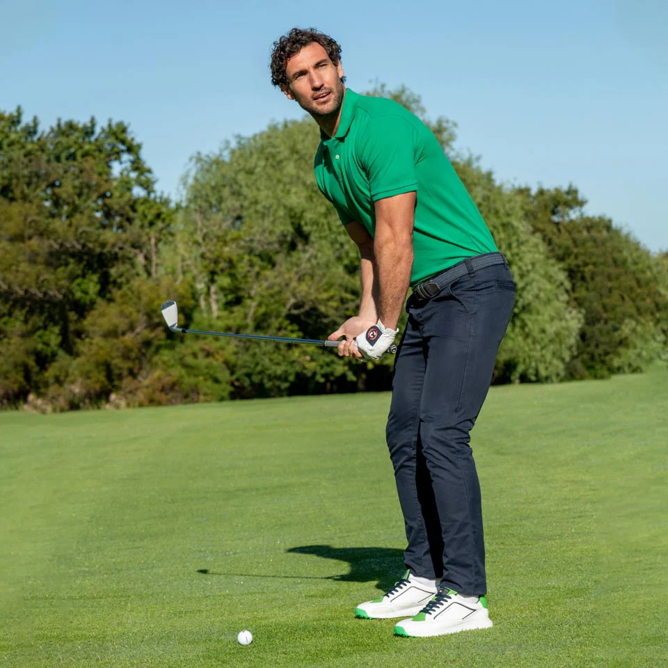 Golfista preparado para el golpe en campo natural con postura profesional.